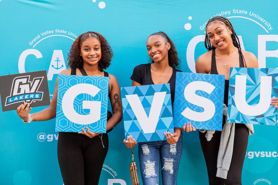 three girls holding a sign that says GVSU